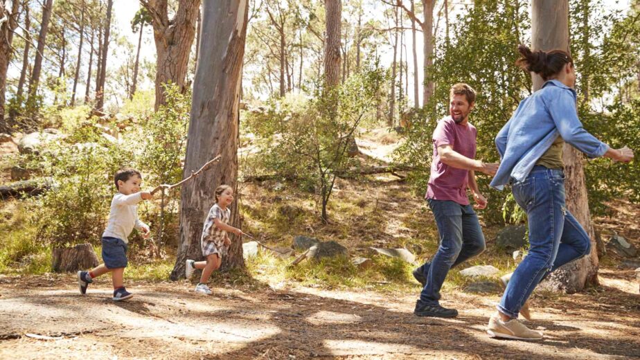 family-running-along-path-through-forest-together-PYZF87D
